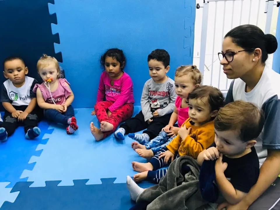 Turma do berçário do Colégio Habitat sentada no tatame com a professora